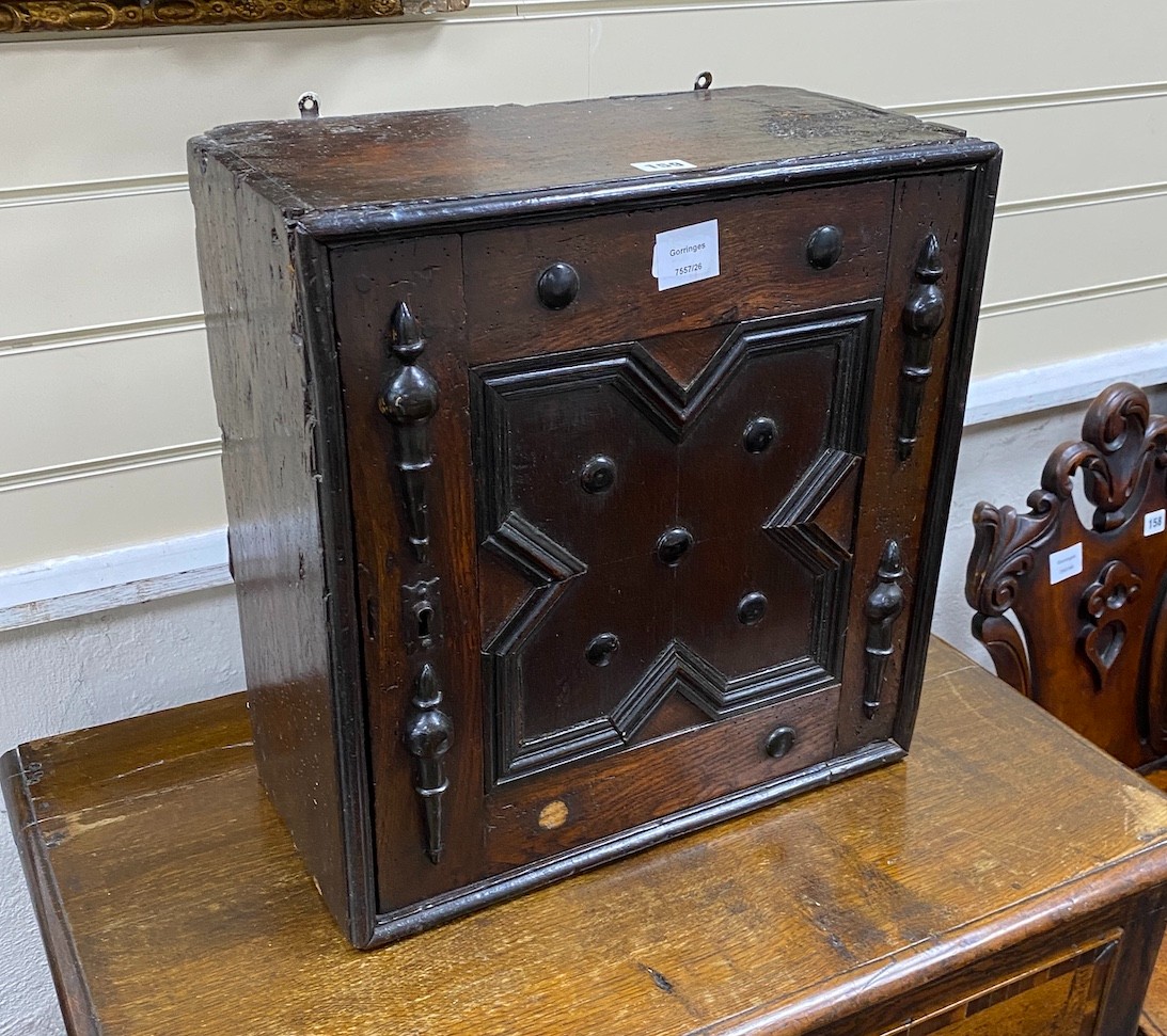 A Jacobean oak spice cupboard, enclosed by a geometric panelled door, width 45cm, depth 23cm, height 46cm